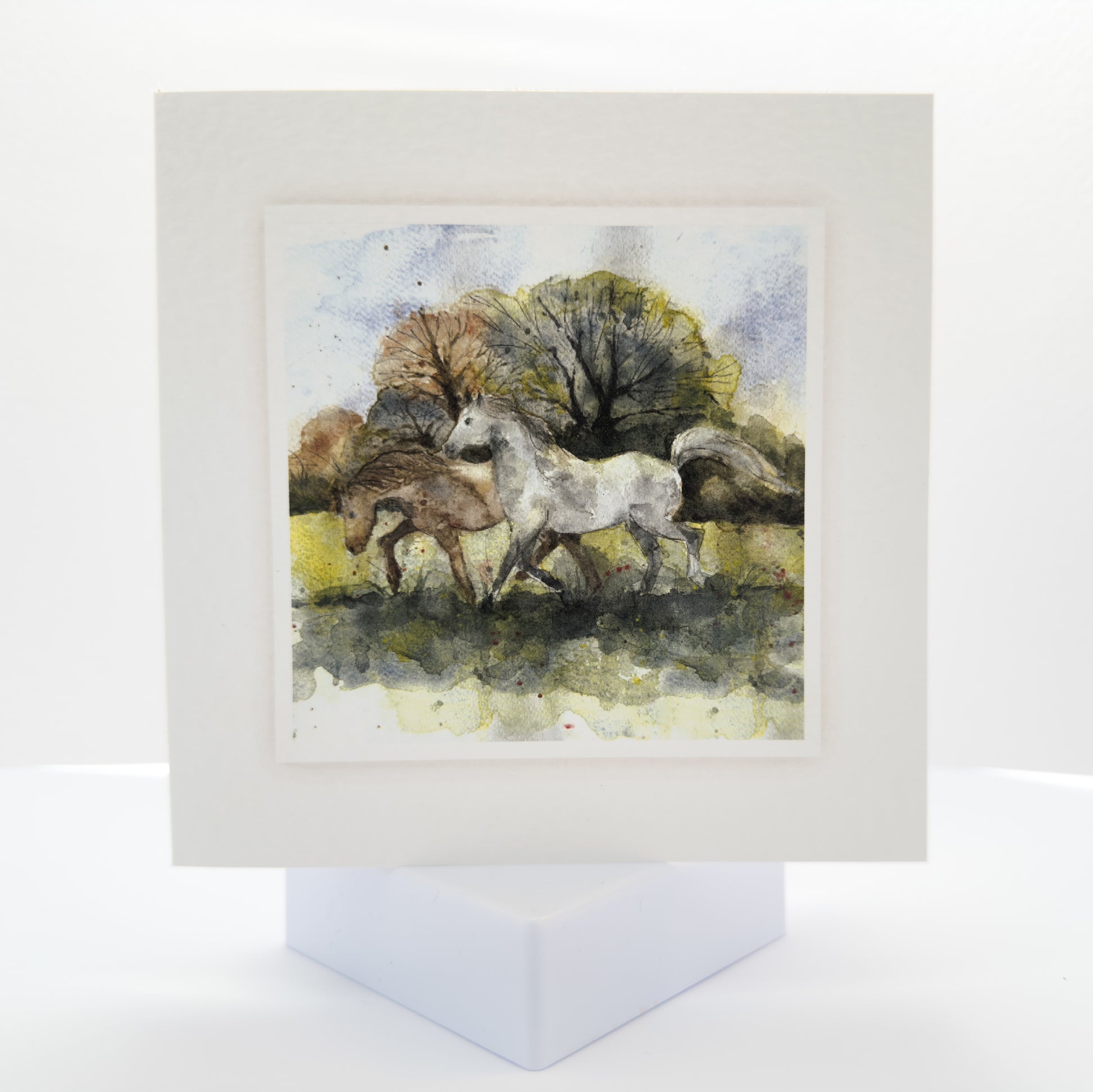 watercolour painting of two horses galloping in a field
